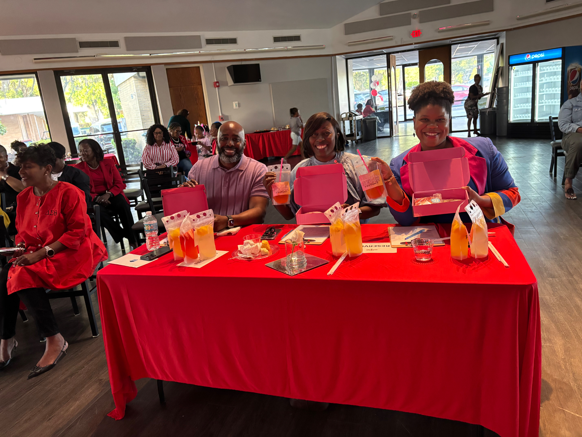 Happy guests holding Sugar Factory cookie boxes and fresh lemonades